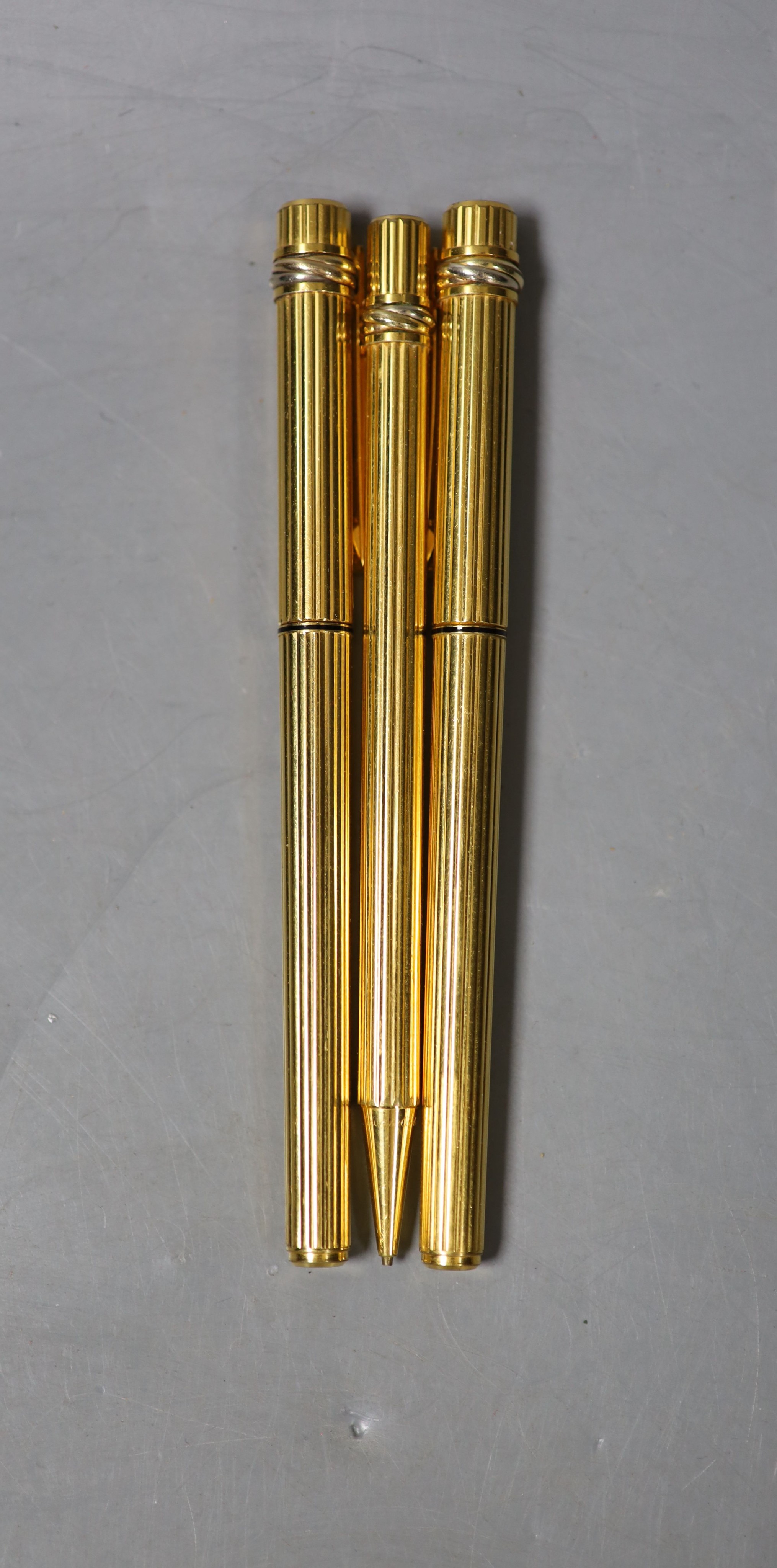 A Cartier gilt metal fountain pen, ball point pen and propelling pencil